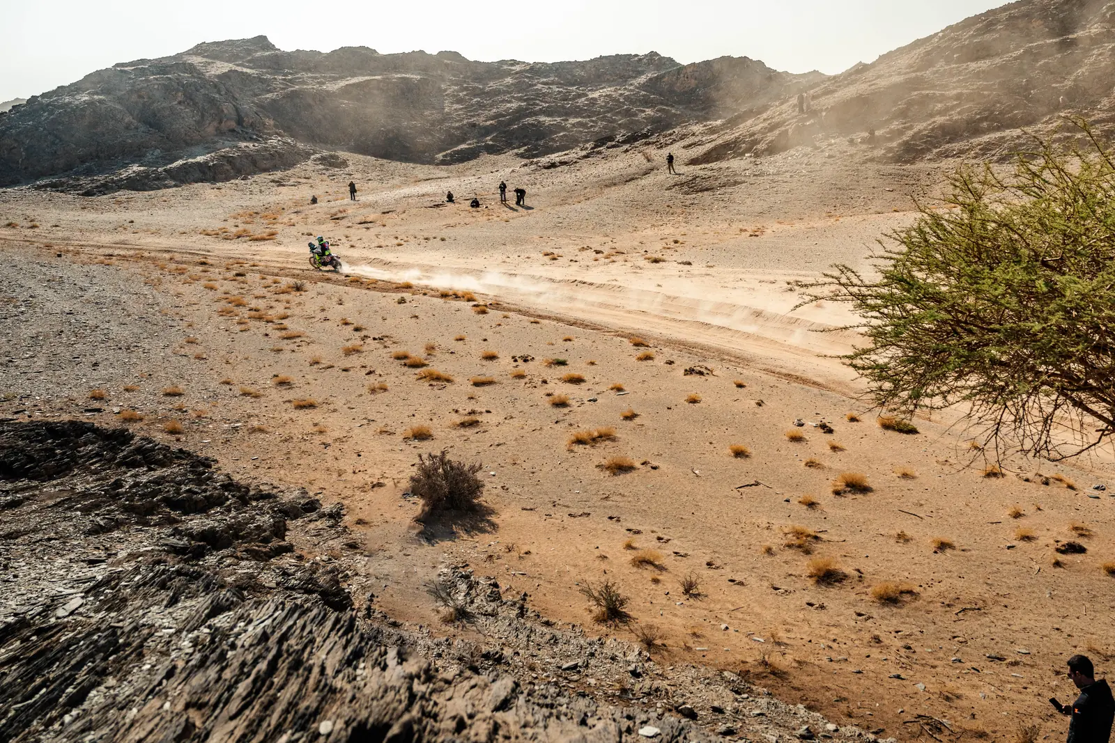 Una pista nel deserto roccioso con un pilota in lontananza, Dakar 2025